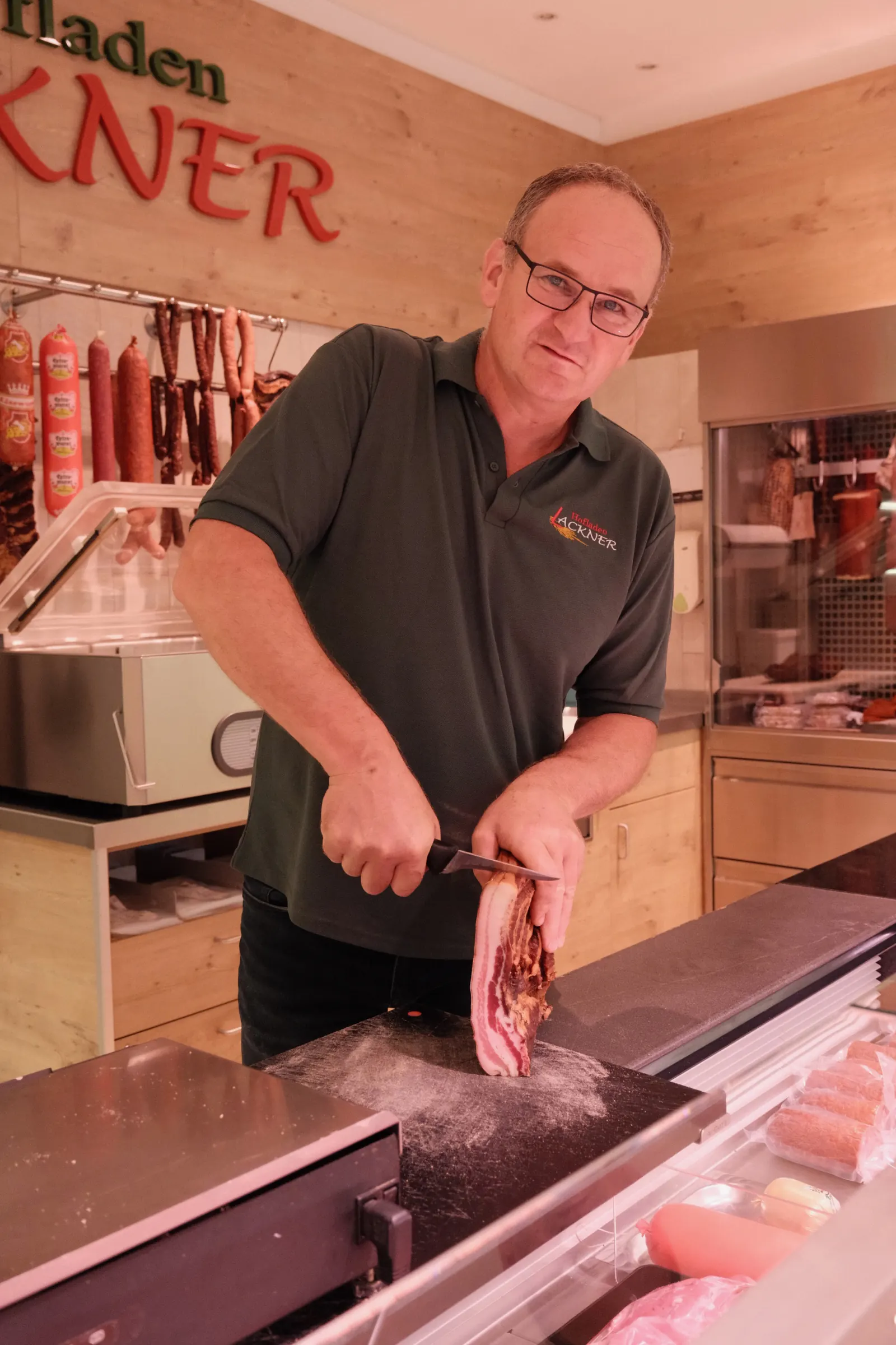 Heinrich schneidet Fleisch im Hofladen Lackner an